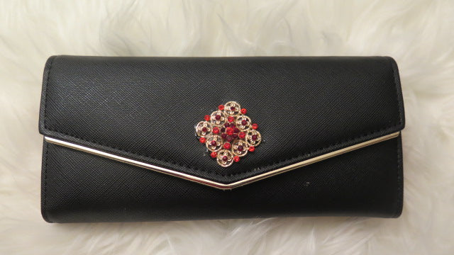A black faux leather wallet with a decorative floral-like pattern on the front and a metallic clasp.