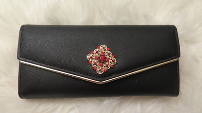 A black faux leather wallet with a decorative floral-like pattern on the front and a metallic clasp.