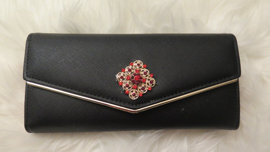 A black faux leather wallet with a decorative floral-like pattern on the front and a metallic clasp.
