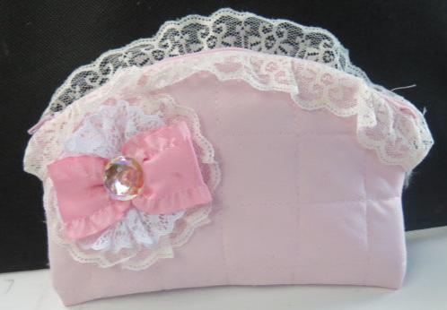 A pink clutch bag with a bow detail and lace trim.
