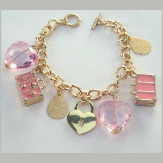 A gold chain bracelet adorned with pink charms, including a heart-shaped lock, a pink bead, and a small pink box.