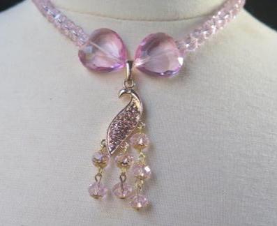 Bow beads clear pink necklace with peacock pendant close up