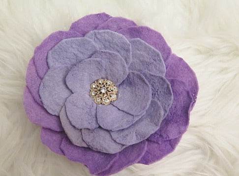 A purple felt flower brooch with a rhinestone center.
