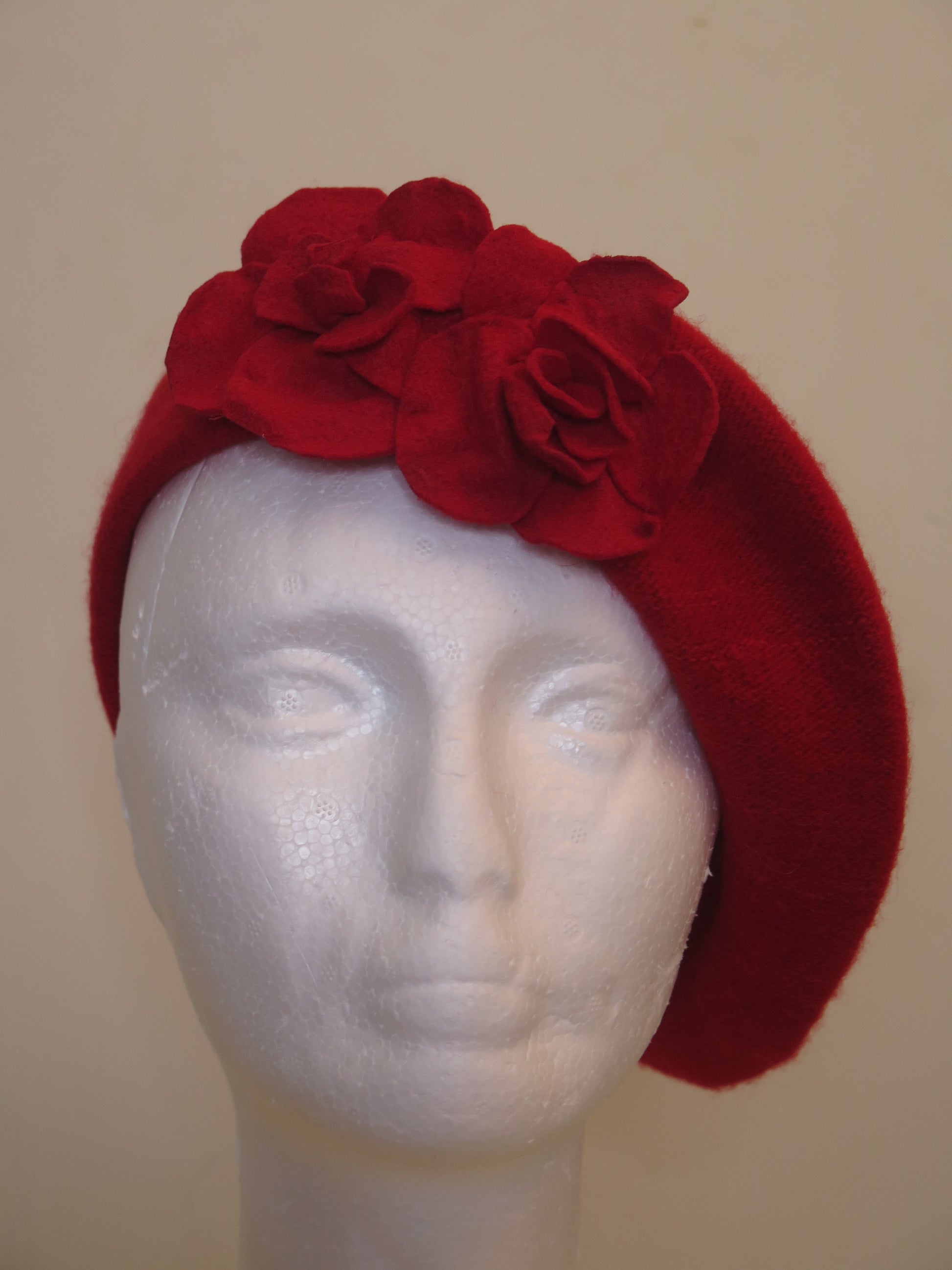 A red wool beret hat with a floral pattern.