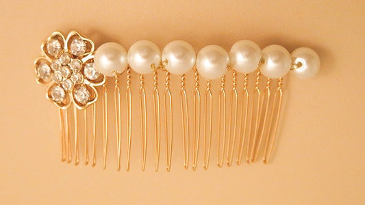 A gold-colored hair comb with pearl and rhinestone embellishments.