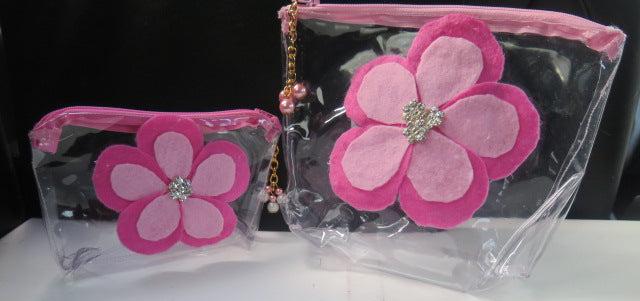 Two clear plastic makeup bags with pink flower decorations, one larger than the other.