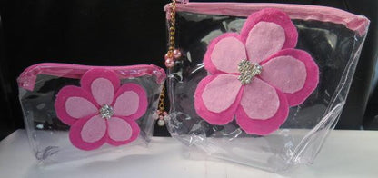 Two clear plastic makeup bags with pink flower decorations, one larger than the other.