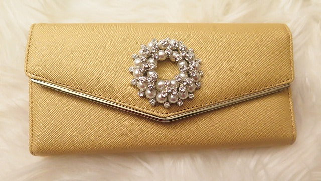 A yellow wallet with a rhinestone embellishment in the center.